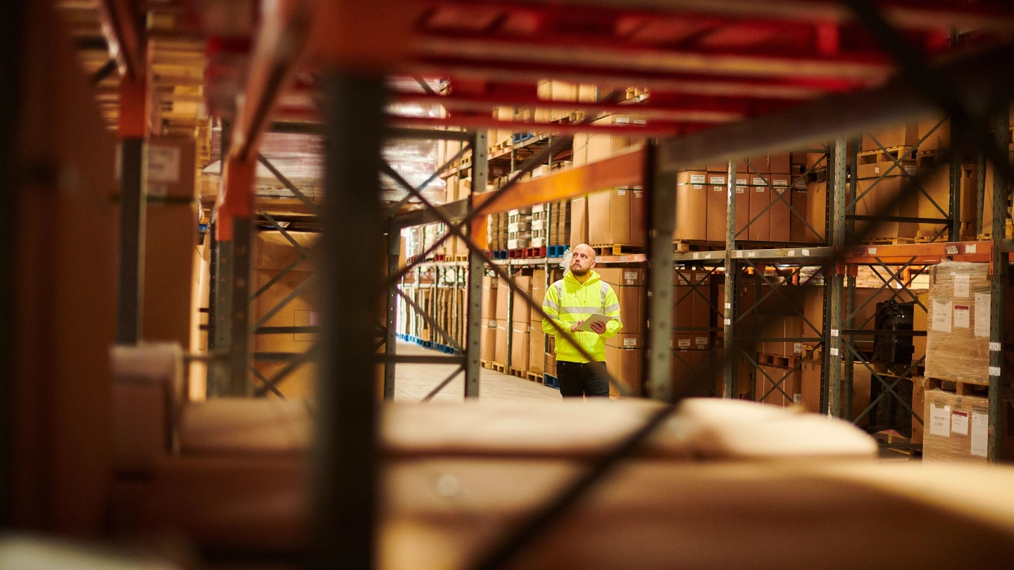 Man walking through warehouse holding a clipboard image