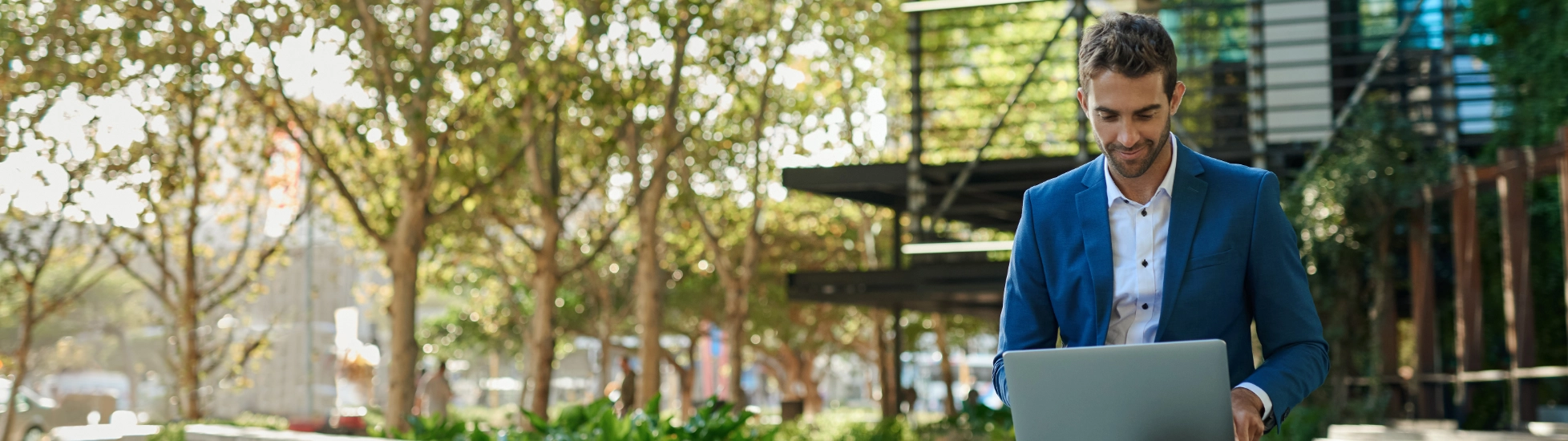 young businessman working online with laptop sitting outside