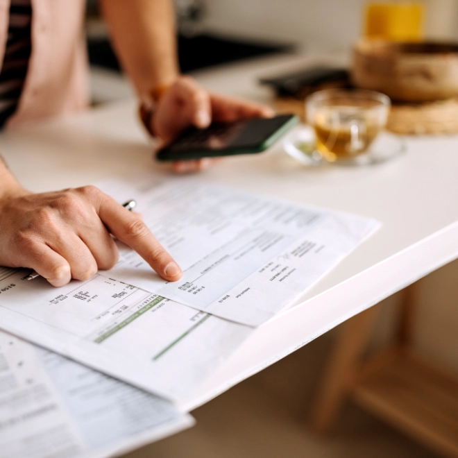 man pointing at sheet and holding mobile phone
